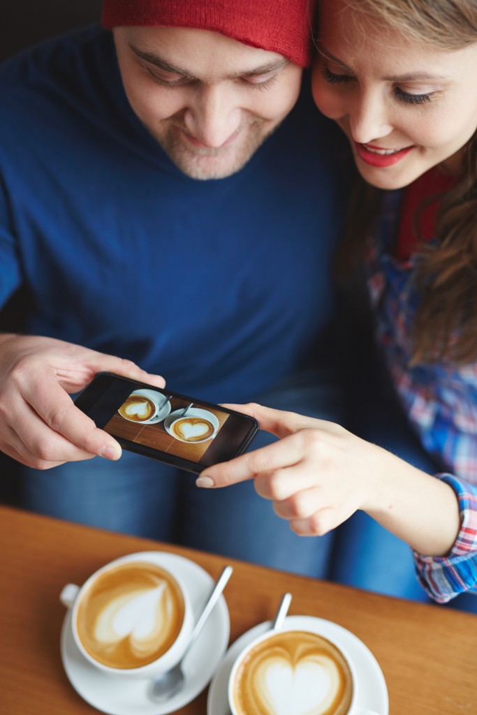 Amorous dates making photo of their coffee in cafe