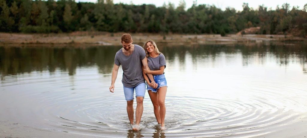 Couple holding hands as they wade in a pond