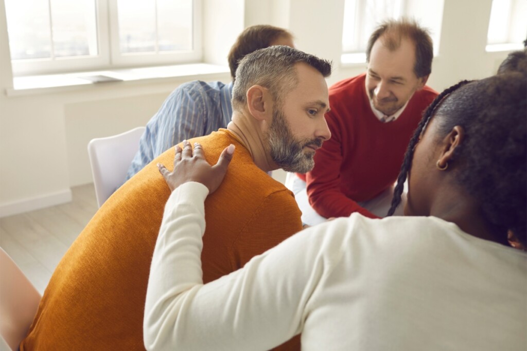 A man in an AA meeting receiving support.